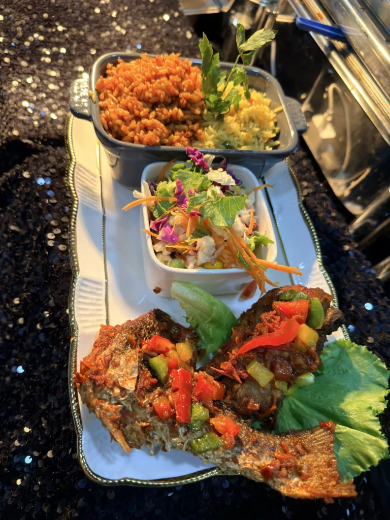 Cabbilicious Foods party jollof rice, coleslaw and peppered fish on a serving platter