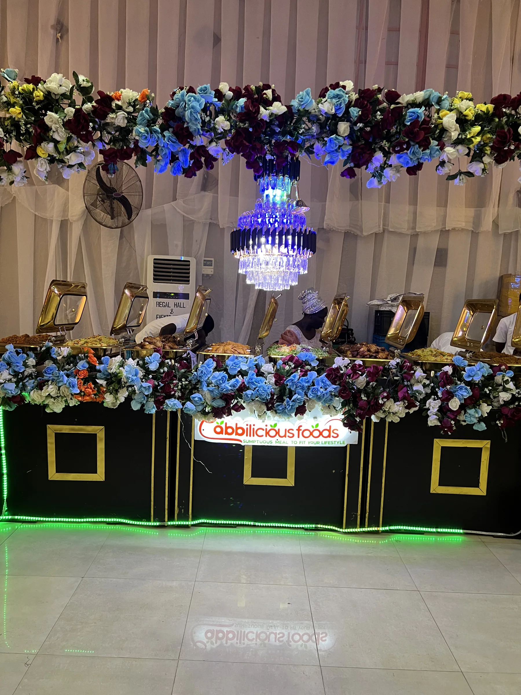 Cabbilicious Foods buffet station with floral display and chafing dishes at an event