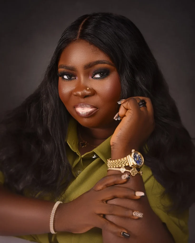 Close-up portrait of Blessing Bashorun in an olive shirt, hand raised to her face, wearing a gold watch